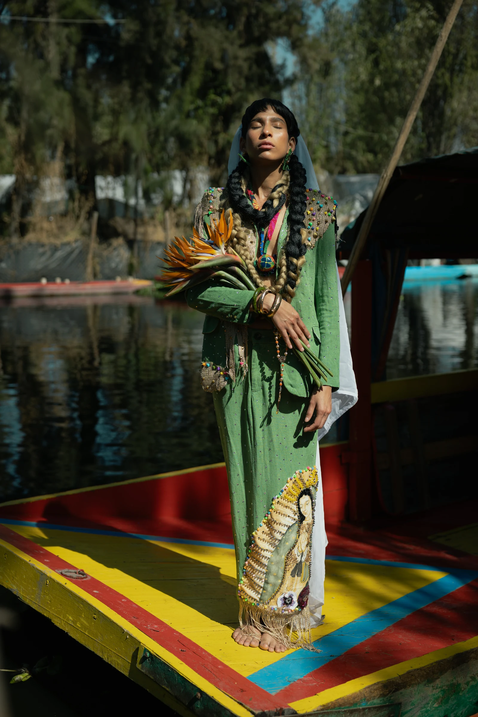 Ticualtzin: traje verde completo sobre una trajinera, con el bordado y los pies visibles